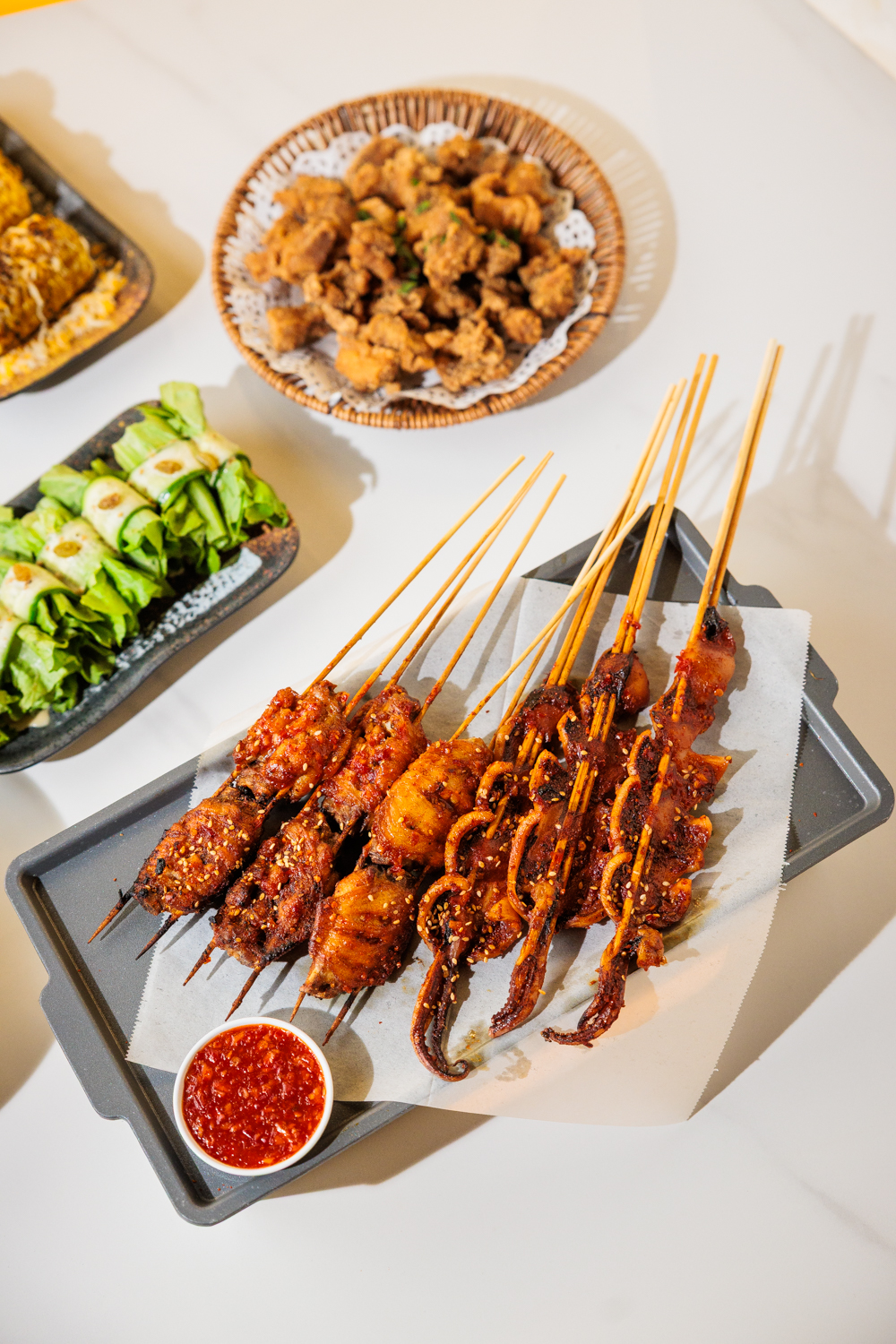 Full table — skewers, wings, salad, corn, and Coronas on ice
